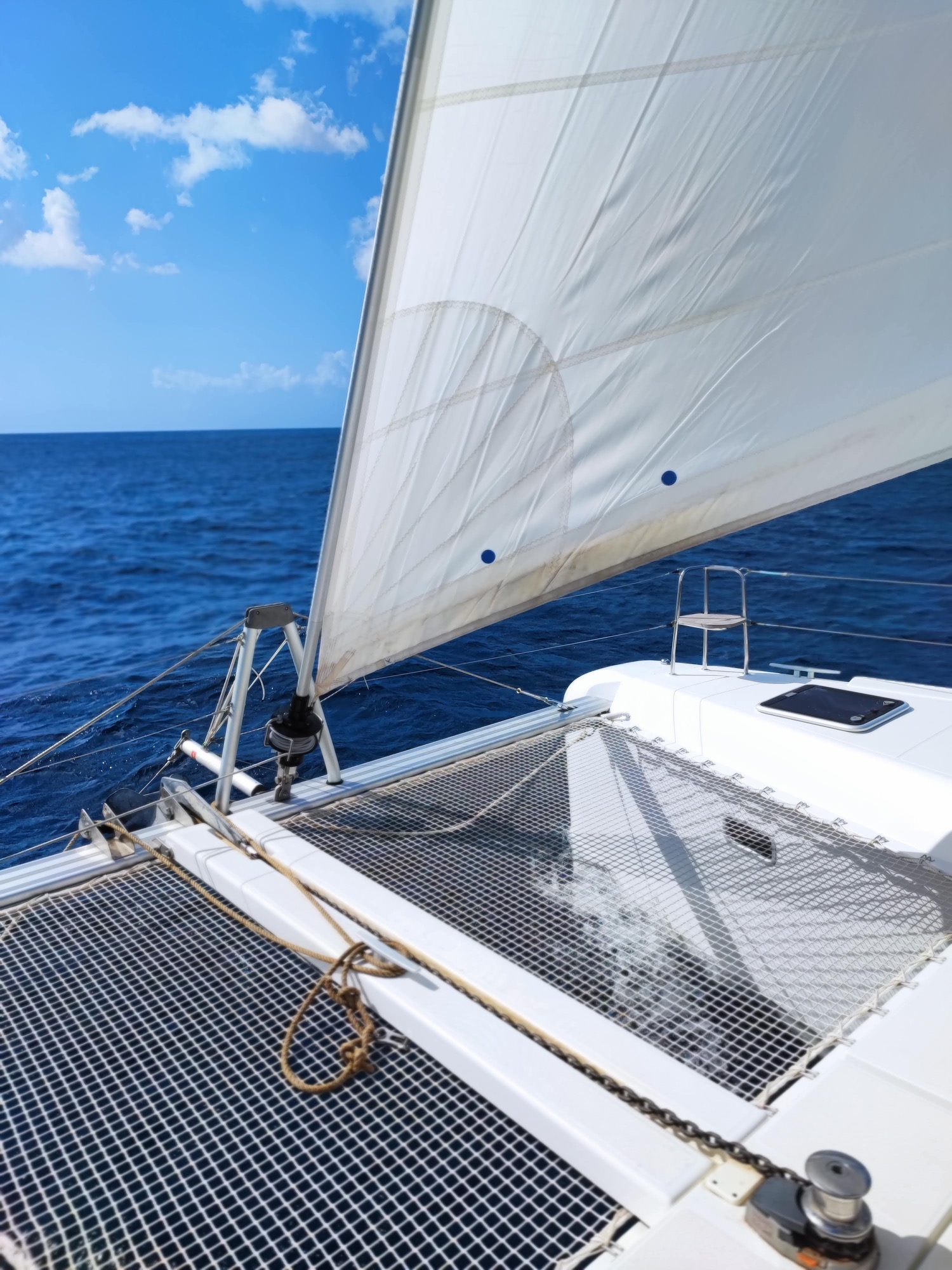 Lagoon 42 2021 Sous voiles Voile blanche d'un catamaran sur une mer bleue sous un ciel dégagé.