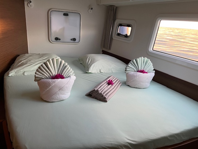 Lagoon 42 2021 Cabine avant Literie de bateau avec des serviettes en forme de fleurs sur les oreillers.