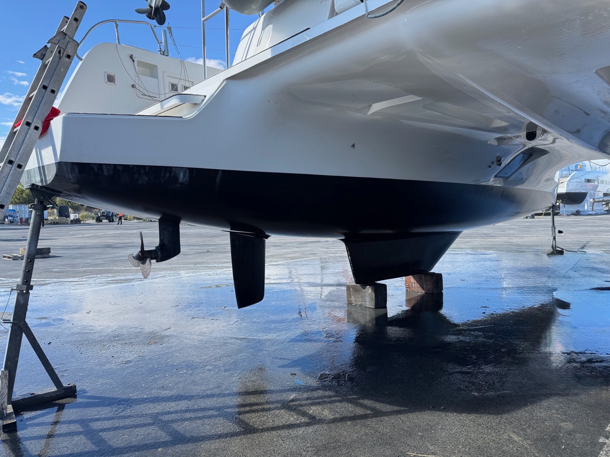 Lagoon 42 2021 A sec Bateau en dehors de l'eau, monté sur des supports, avec une coque blanche et noire.