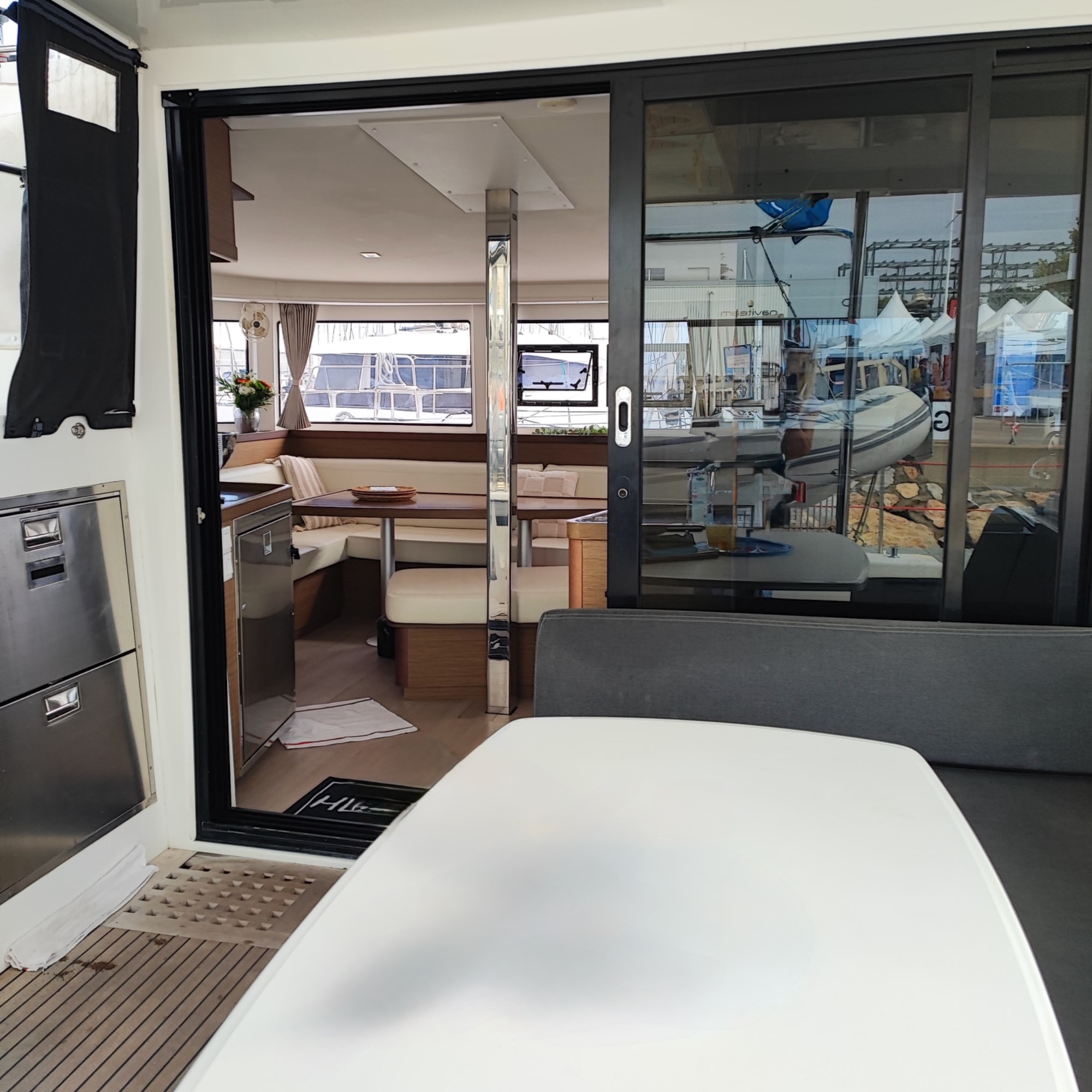 Lagoon 42 2021 Cockpit Intérieur d'un bateau avec un coin salon et une vue sur l'extérieur par des portes vitrées.