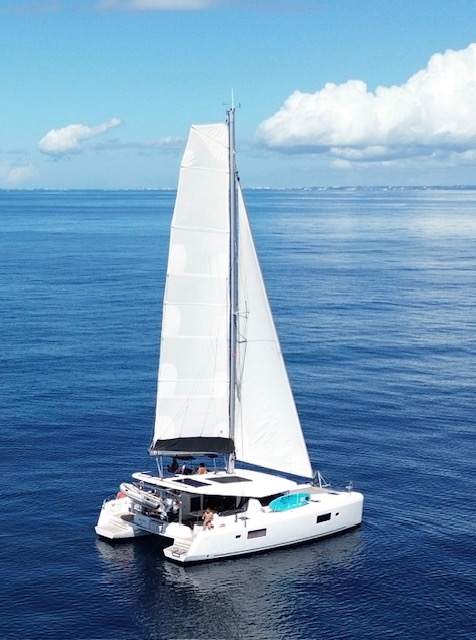 Lagoon 42 2021 Sous voiles Un catamaran à voile naviguant sur une mer calme sous un ciel clair.
