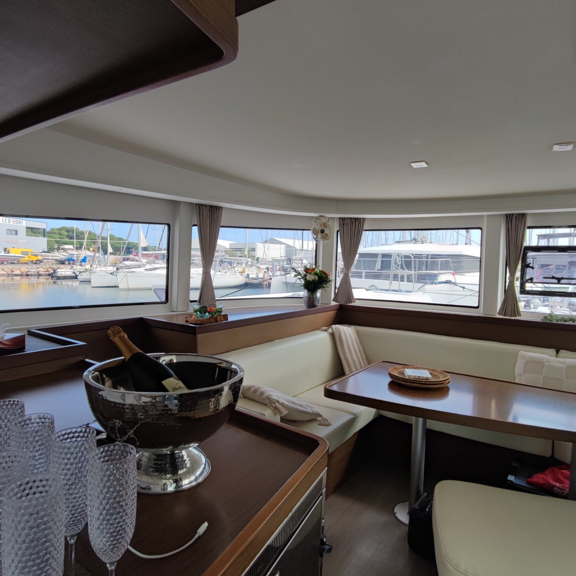 Lagoon 42 2021 Carré Intérieur d'un salon de bateau avec vue sur le port et mobilier moderne.