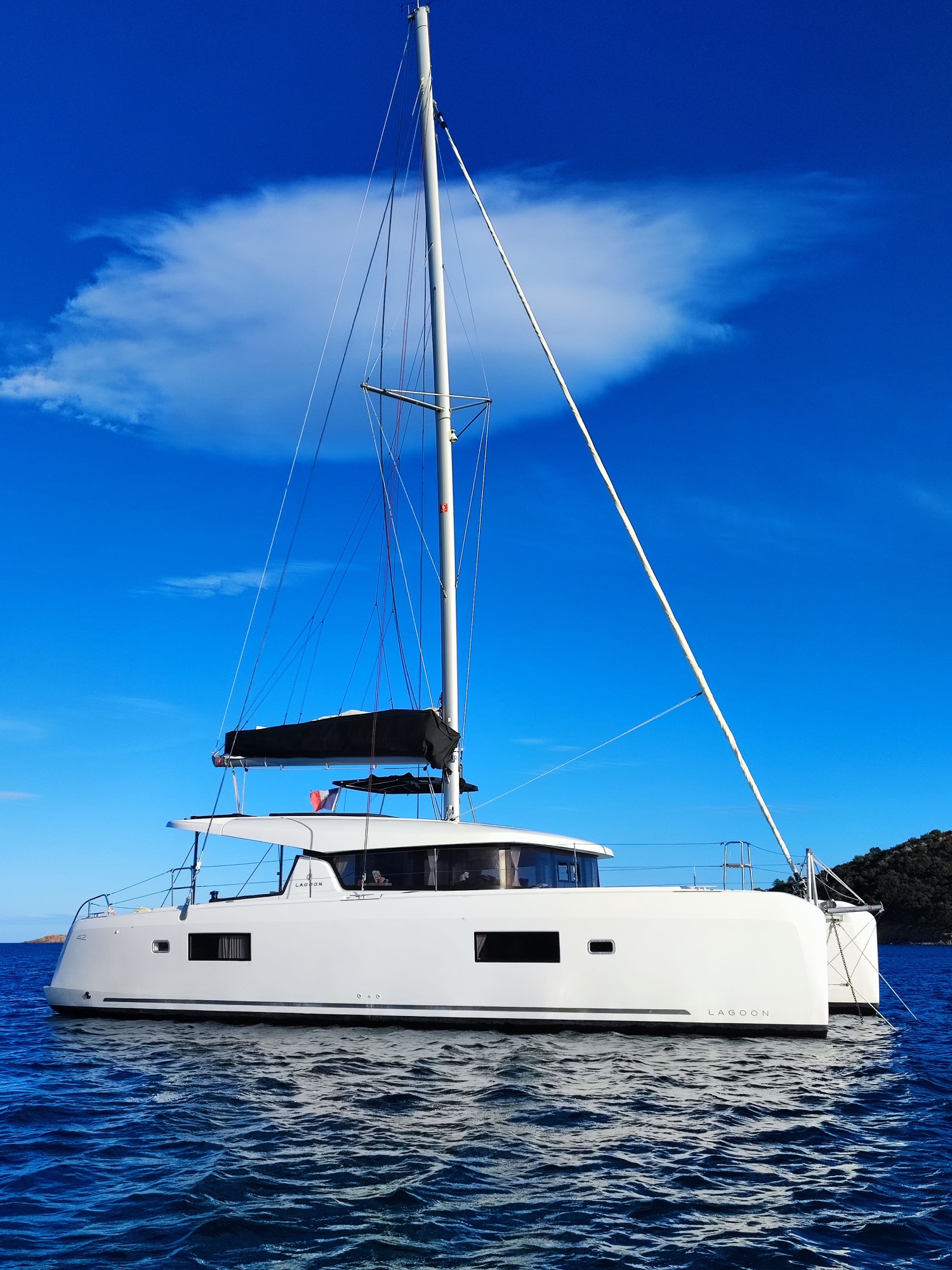 Lagoon 42 2021Au mouillage Voilier blanc à voile sur l'eau, ciel bleu avec quelques nuages.