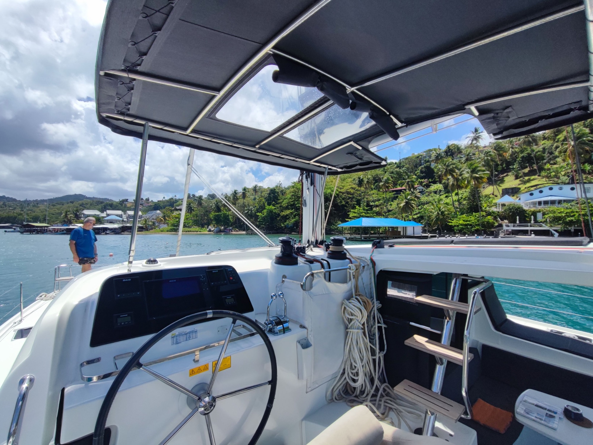 Lagoon 42 2021 Poste de barre Vue intérieure d'un voilier avec un tableau de bord et des paysages côtiers en arrière-plan.