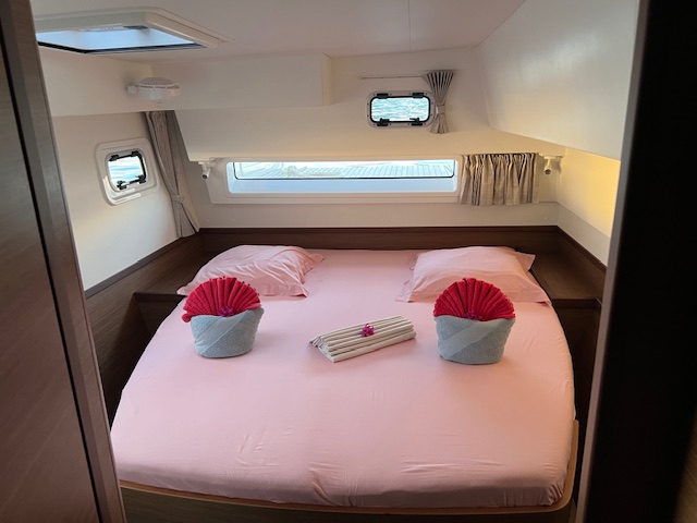 Lagoon 42 2021 Cabine arrière Chambre avec lit double et coussins roses, décorée de manière minimaliste.