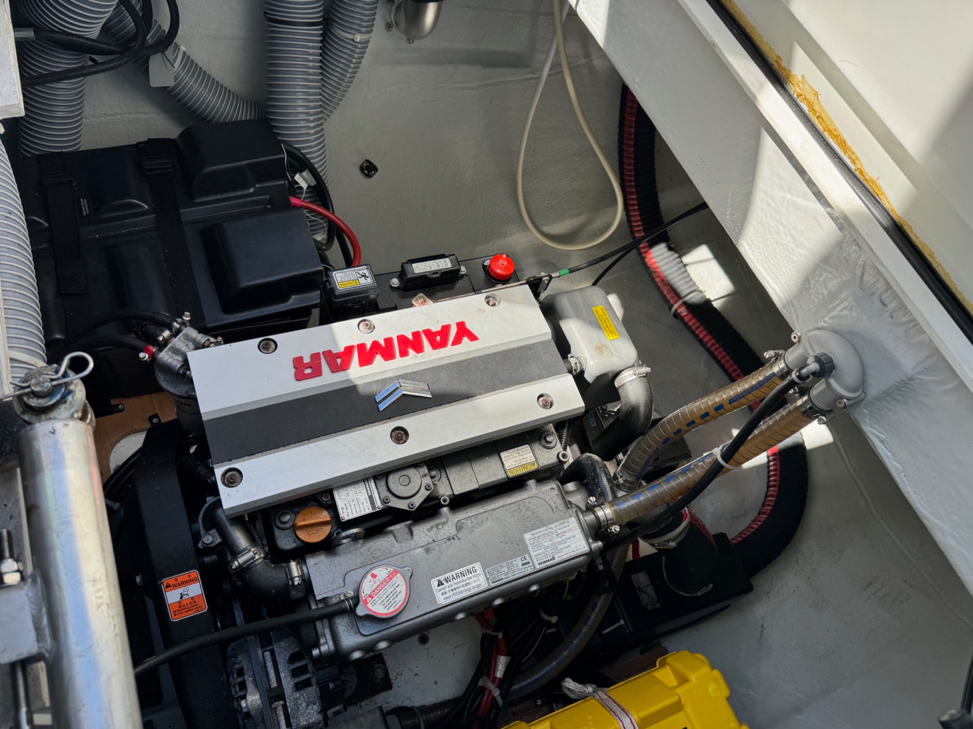 Lagoon 42 2021 Moteur Yanmar 4JH57 Moteur Yamaha installé dans un compartiment de bateau, avec câblage et accessoires visibles.
