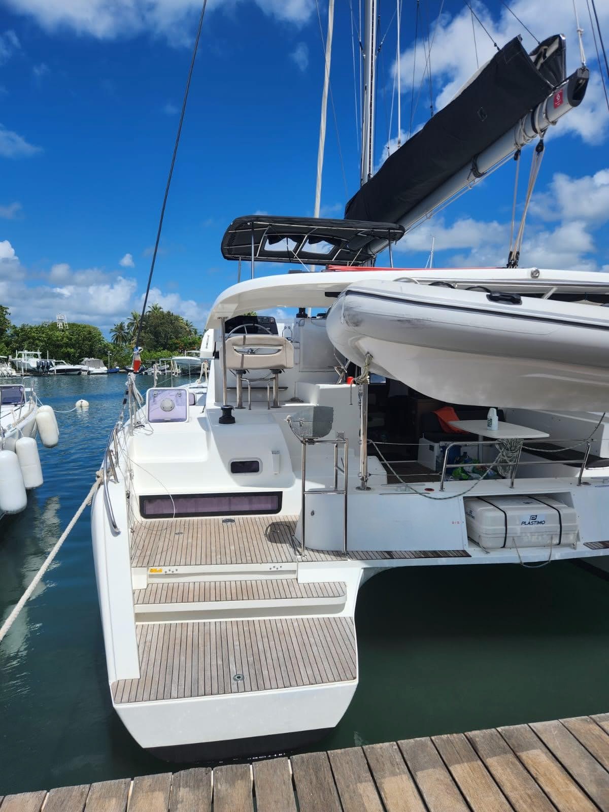 Lagoon 42 2021 Jupe teck Catamaran amarré au port, sous un ciel bleu avec quelques nuages.