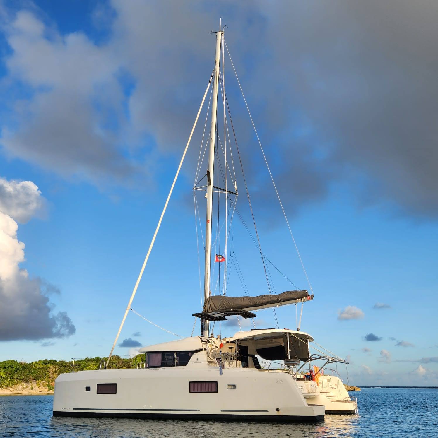 Lagoon 42 2021 Au mouillage Catamaran blanc ancré dans une baie sous un ciel légèrement nuageux.