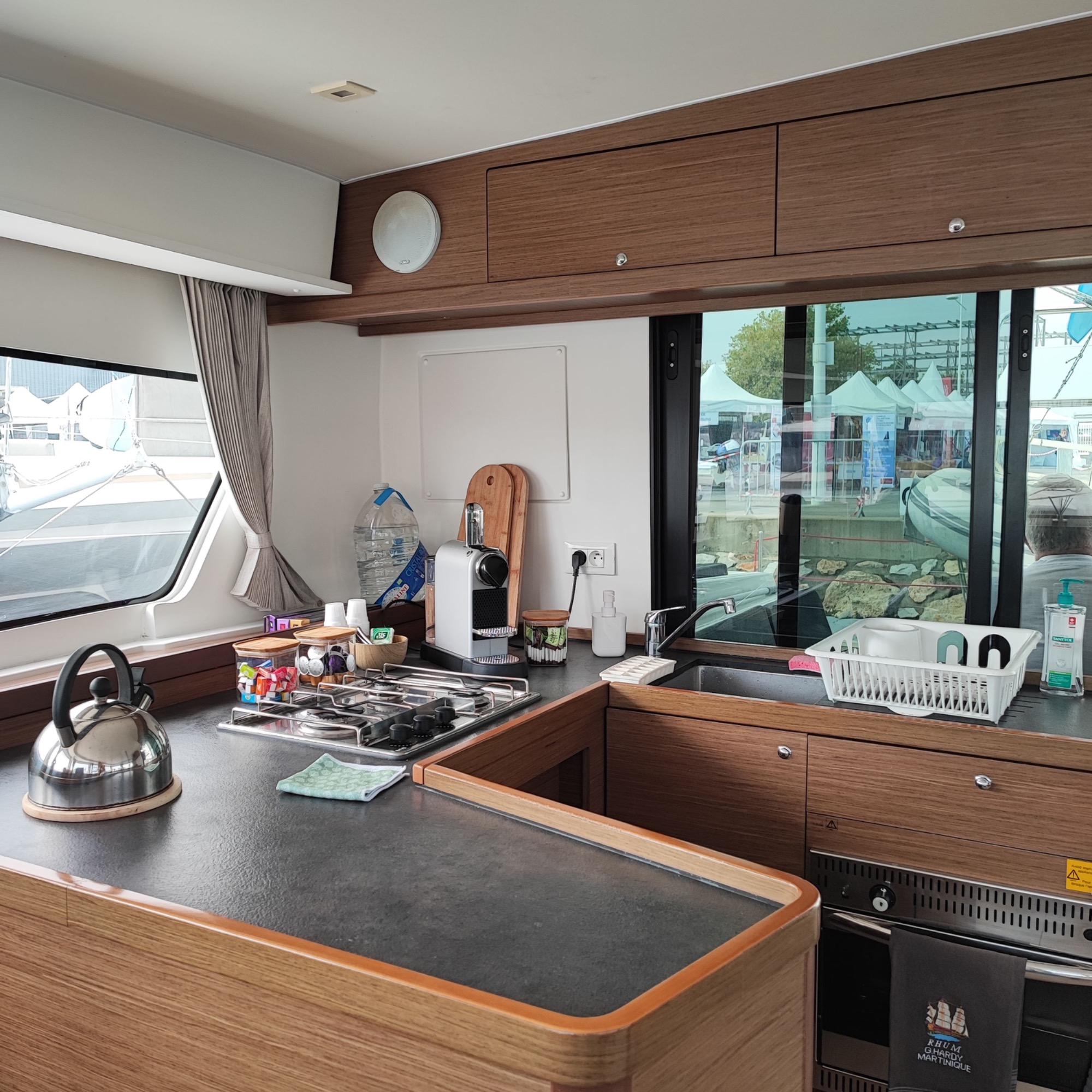 Lagoon 42 2021 Cuisine Intérieur d'une cuisine moderne avec vue sur un port, équipée d'appareils et d'un évier.