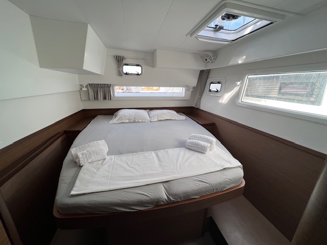Lagoon 42 2021 Cabine arrière Chambre avec lit double, draps blancs et fenêtres laissant entrer la lumière.