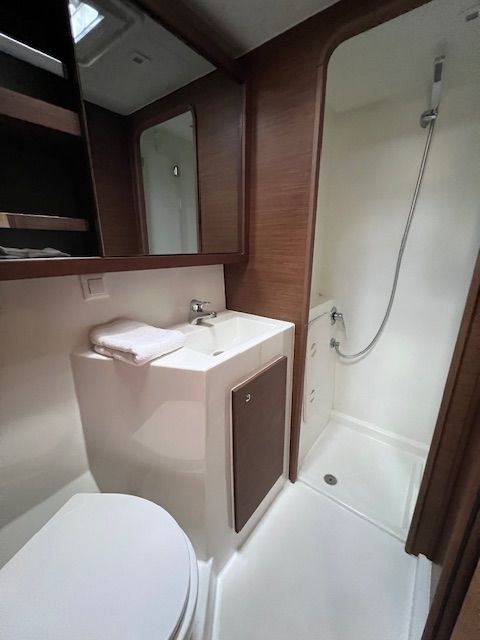 Lagoon 42 2021 Salle de bain cabine arrière Salle de bains avec douche, lavabo et toilettes intégrées. Murs clairs et mobilier moderne.